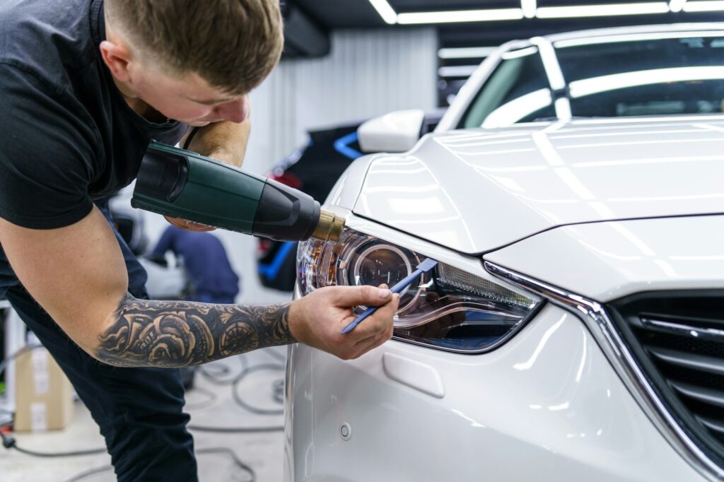 Sticker of a protective film on the headlight of a car in a car detailing studio